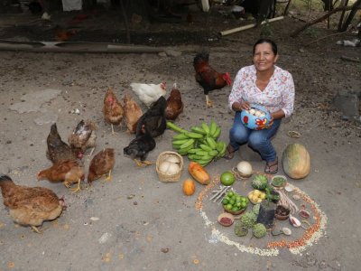 Eine Kleinbäuerin aus Kolumbien zeigt stolz ihre Nahrungsmittel, die sie aus bäuerlichem Saatgut produziert.