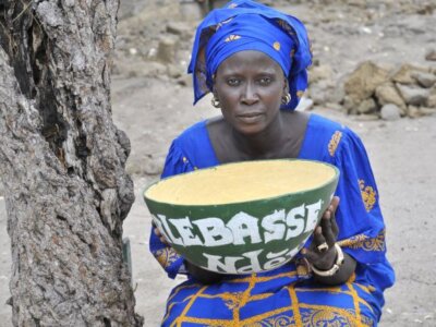 Eine senegalesische Frau hält eine Kalebasse in ihren Händen