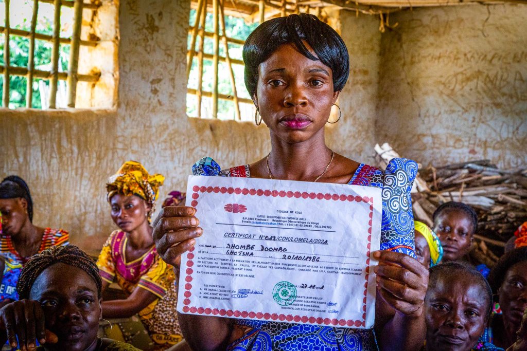 Carine Shombe Dombo hält das Zertifikat ihres Alphabetisierungsprogramms in der Hand.